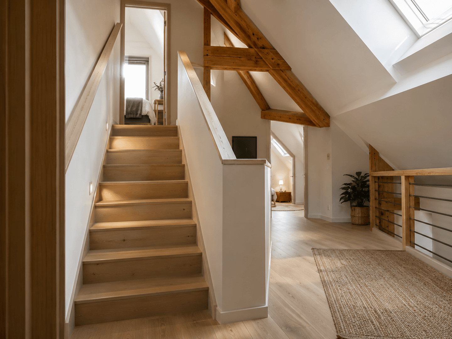 Escalier installé sous une charpente apparente.